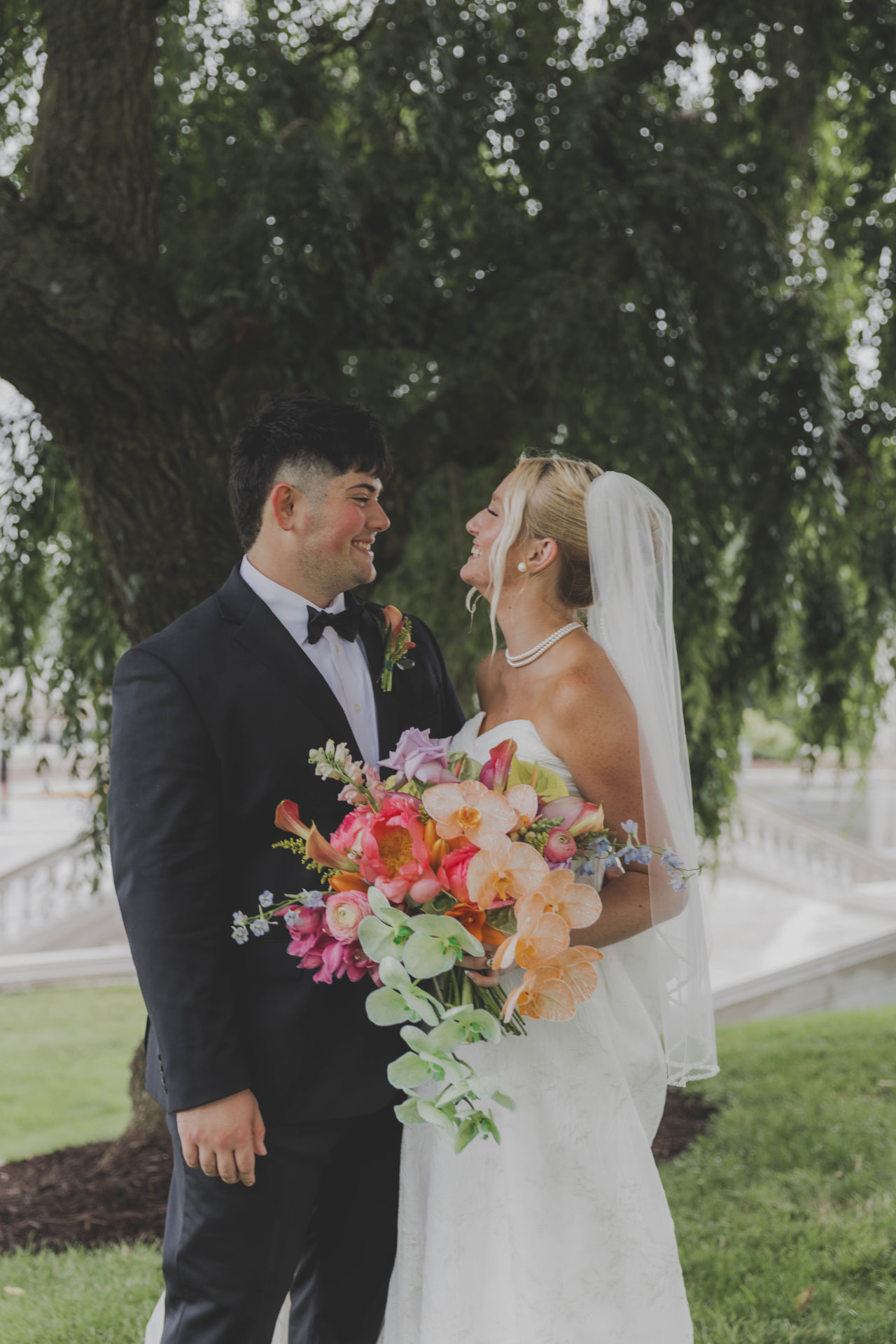 Bride and groom laughing together under a willow tree during Missouri wedding portraits